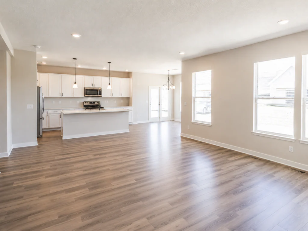 Living room before virtual staging: bright open-plan room with a white kitchen, shown empty.